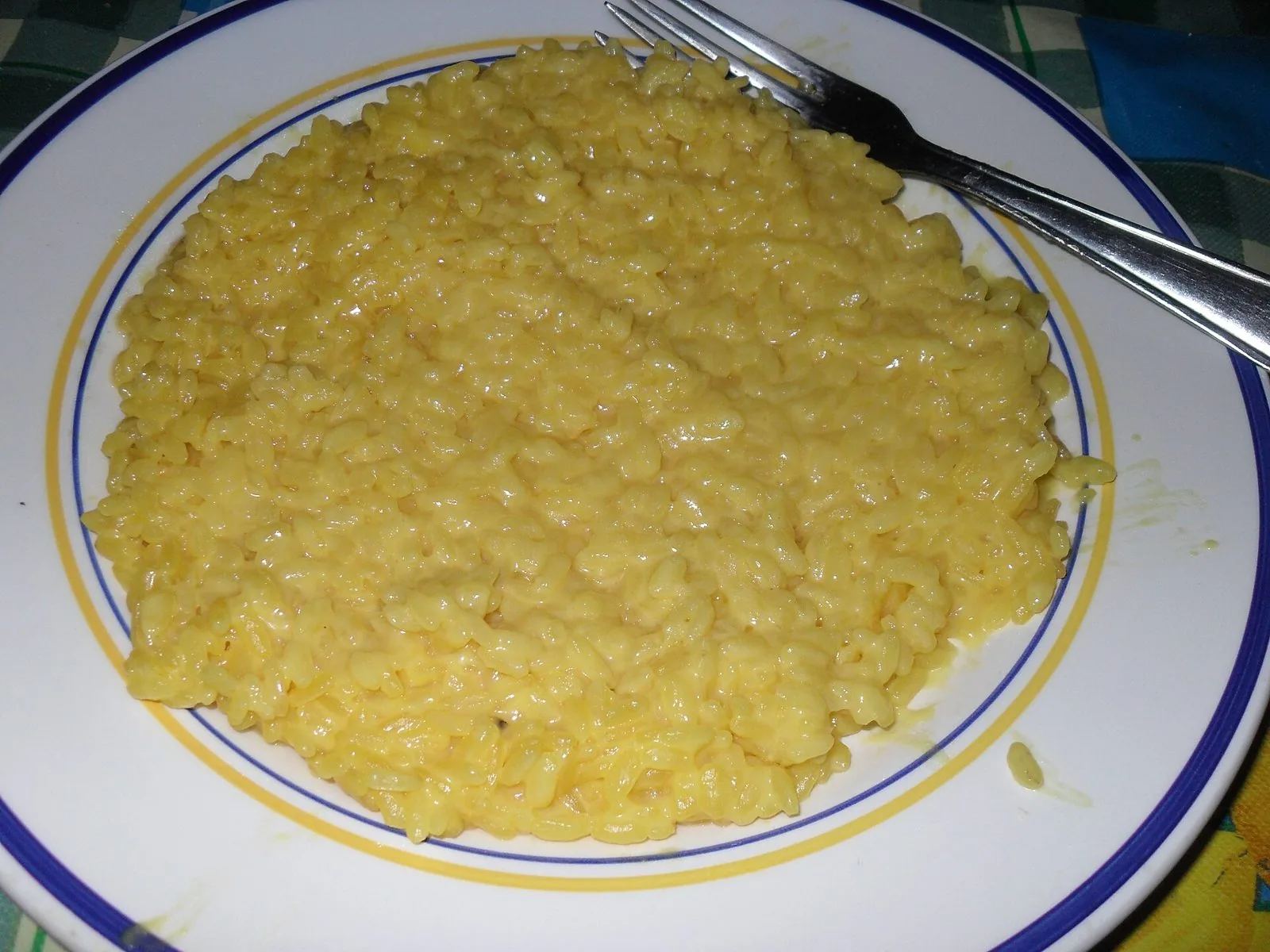 Piatto di risotto alla milanese giallo allo zafferano con forchetta
